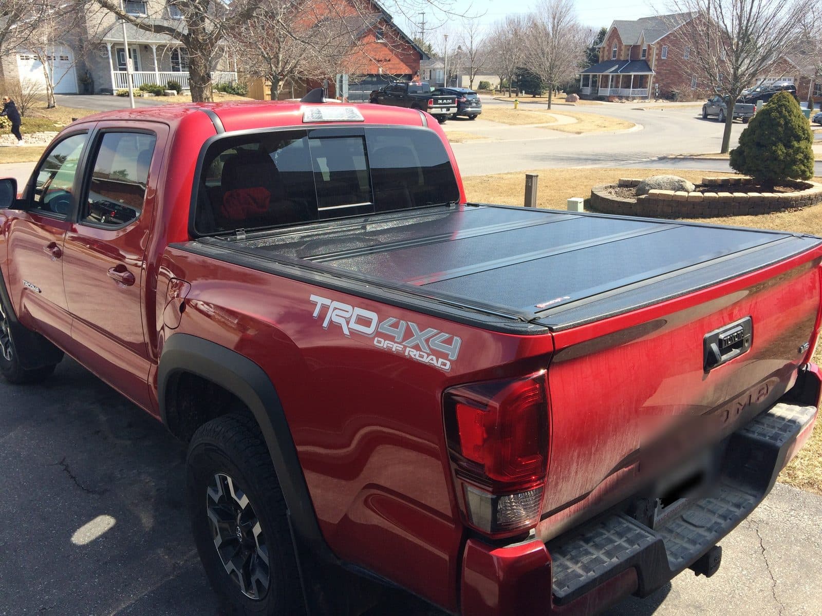 Hard tri-fold tonneau cover closed on a red Toyota Tacoma